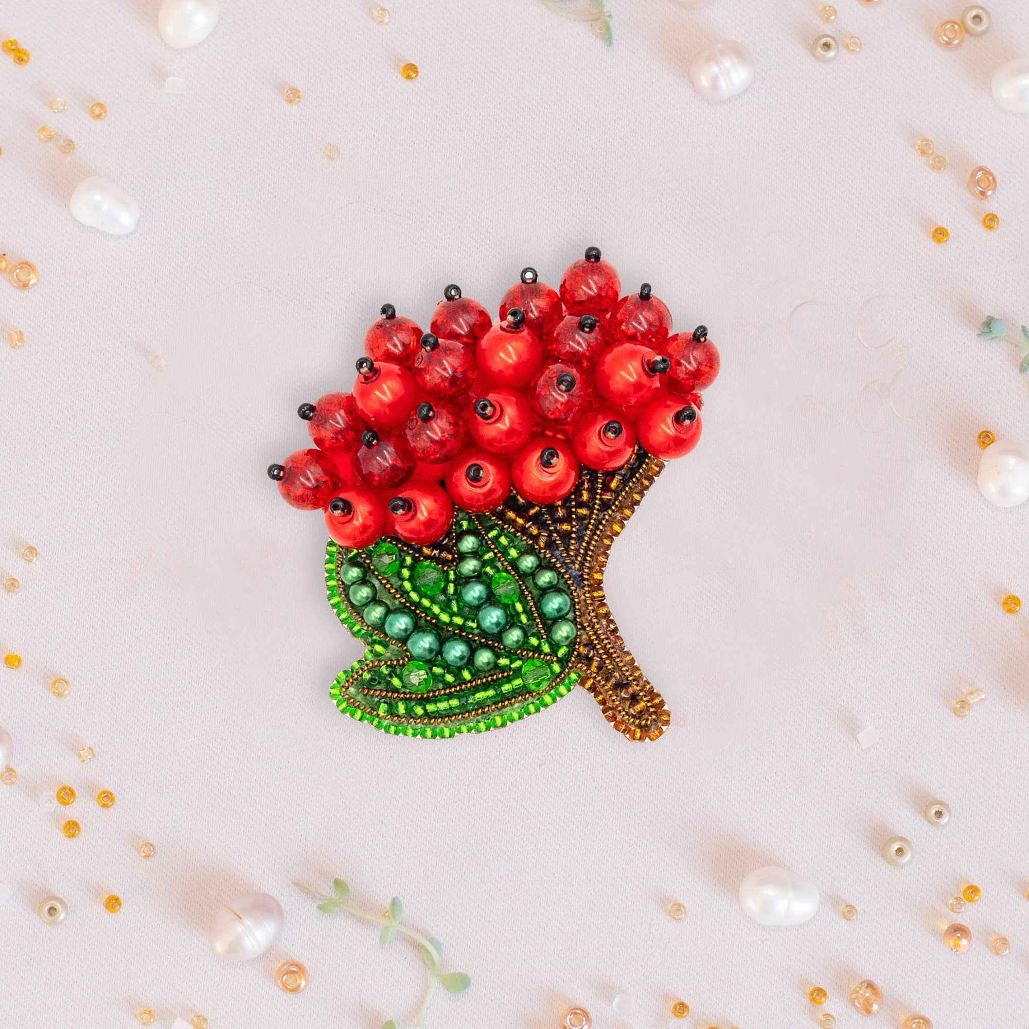 a brooch with red flowers and green leaves